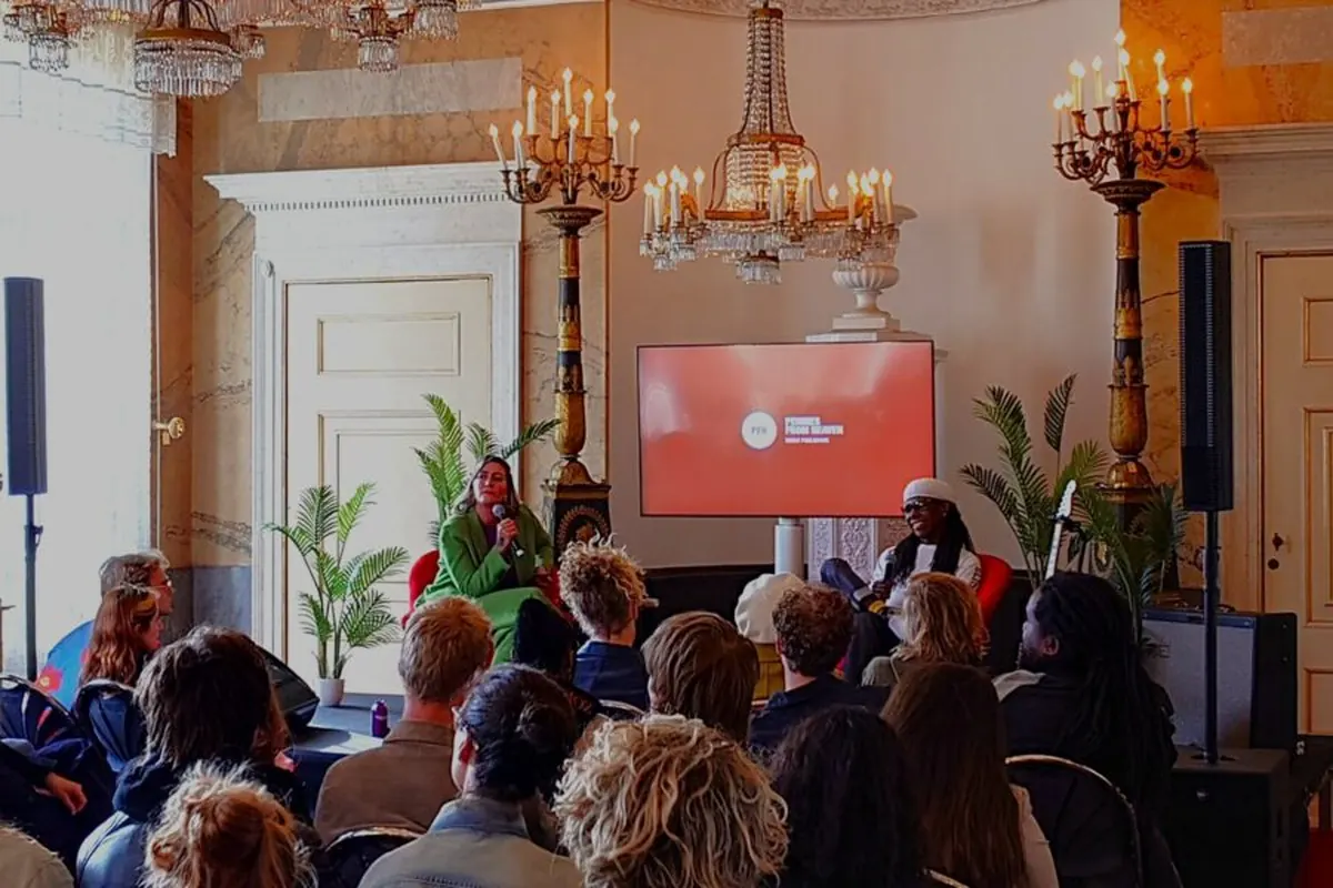 Presentatiemonitor achter twee deelnemers tijdens een bijeenkomst